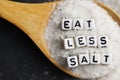 Eat less salt advice written with plastic letter beads on granulated salt Ã¢â¬â healthy food lifestyle